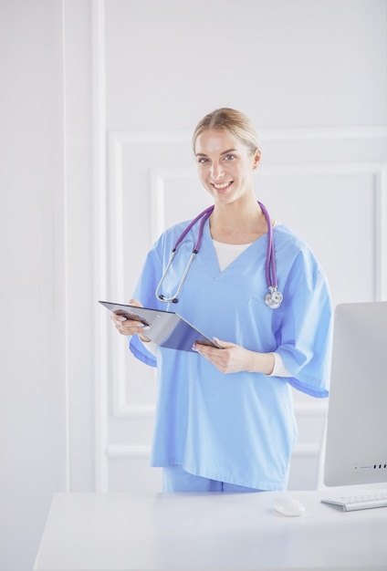 Smiling female doctor with a folder in uniform standing