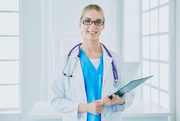 Smiling female doctor with a folder in uniform standing