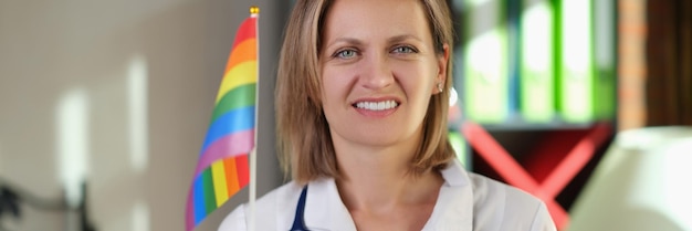 Smiling female doctor with lgbt flag in her hand in clinic office medical care for support lgbt