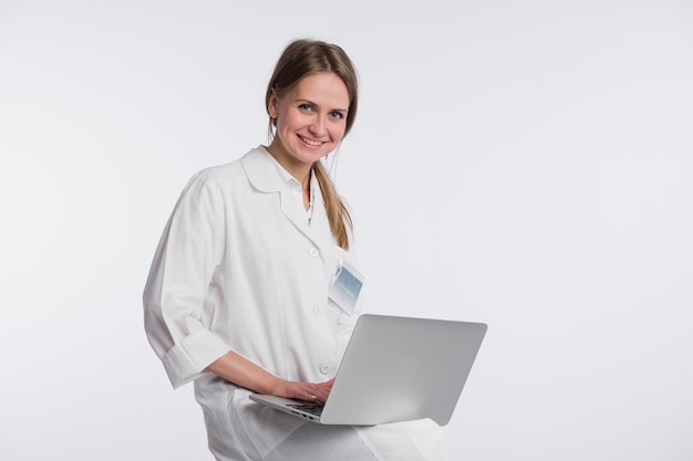 Smiling female doctor working on her laptop against a white