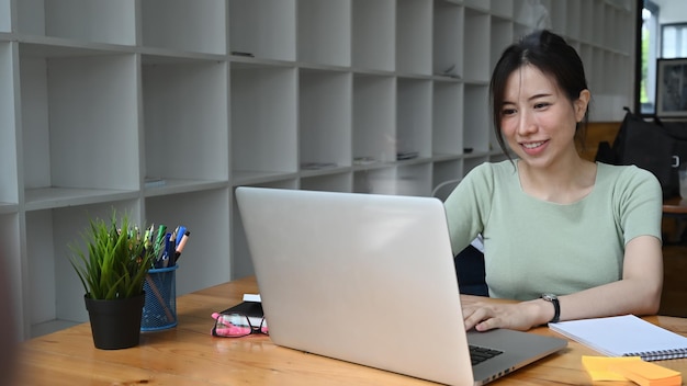 Smiling female entrepreneur working with laptop computer