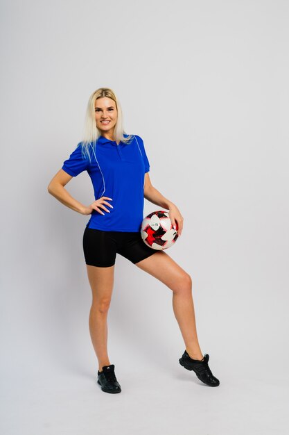 Smiling female football player with ball isolated on white background