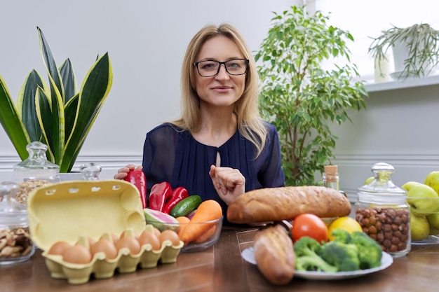 Smiling female nutritionist looking at camera with food set on table