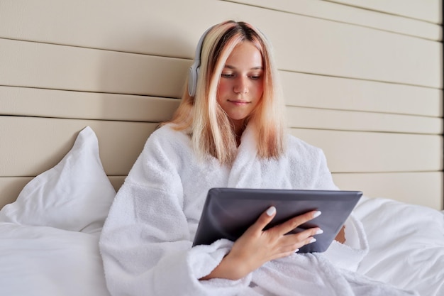 Smiling female teenager in headphones with digital tablet