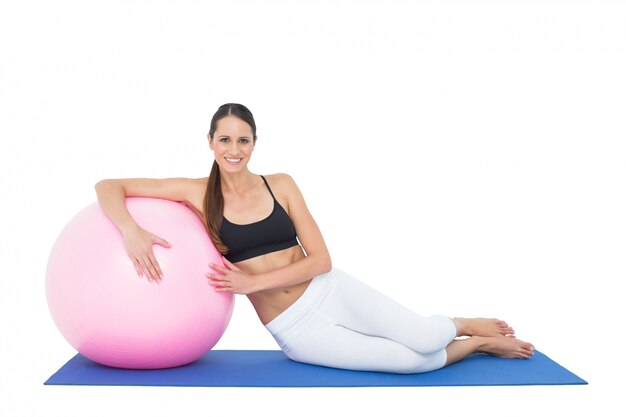 Smiling fit young woman sitting with fitness ball