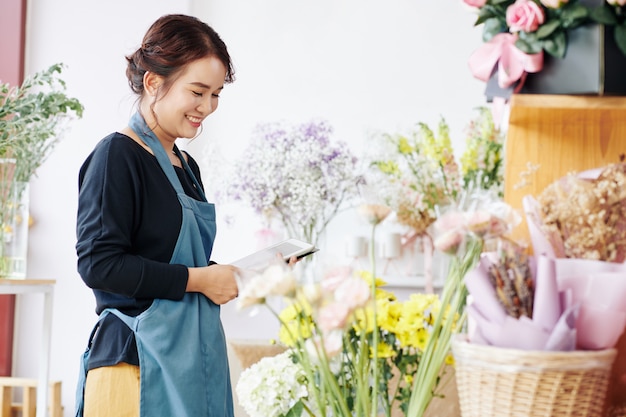 Smiling florist checking flowers in shop