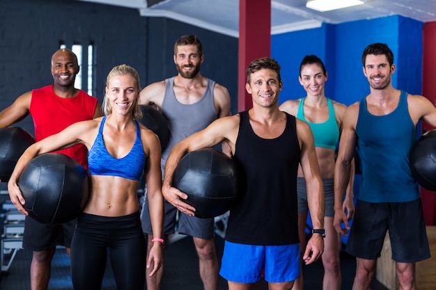  smiling friends holding exercise ball in gym