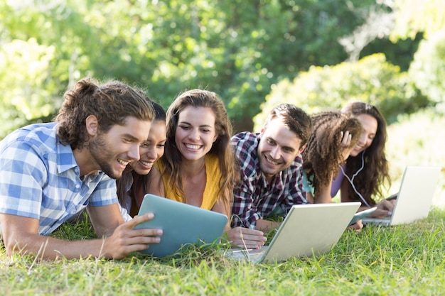 Smiling friends in the park using tablet pc and laptop