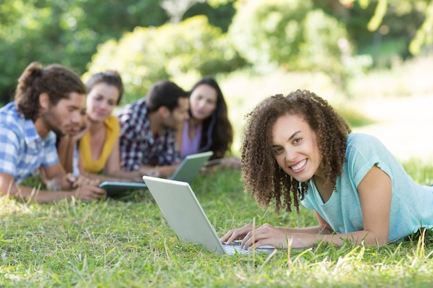 Smiling friends in the park using tablet pc and laptop