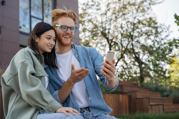 Smiling friends using mobile phone shopping online