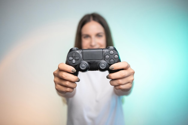 Smiling fun woman holding console controller on colorful background. Young adult person enjoying