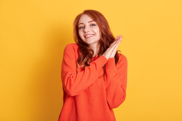 Smiling ginger girl wearing casual clothing looking  and keeping palms together