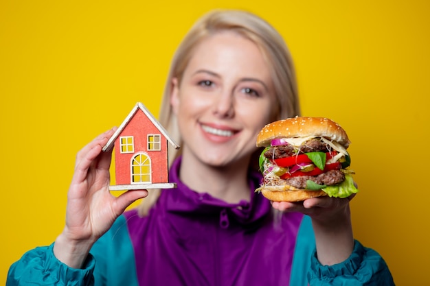 Photo smiling girl in 80s clothes style with burger and home symbol