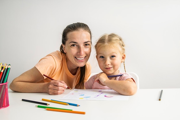 Smiling girl child and mother are painted with colored pencils on paper