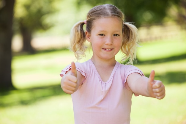 Smiling girl gesturing thumbs up at park