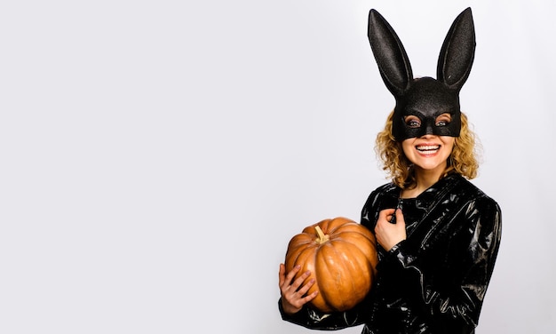 Smiling girl in halloween bunny costume with pumpkin sexy woman in rabbit mask with jackolantern