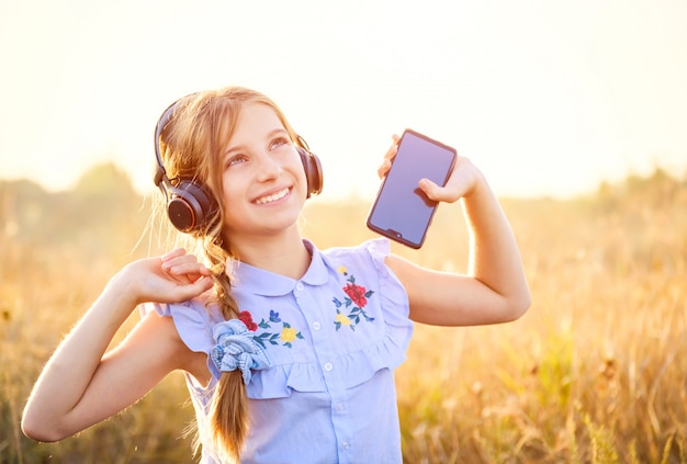 Smiling girl hold smartphone and listening to music with raised hands