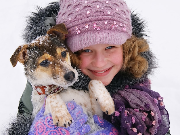 Smiling girl holding a dog, girl and doggie friends, winter, around a lot of snow