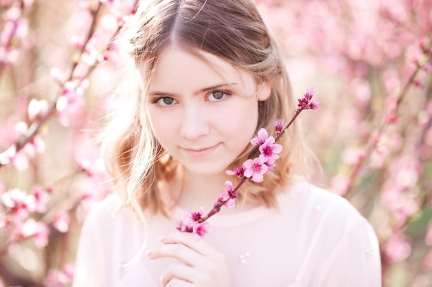 Smiling girl holding flowers in peach orchard