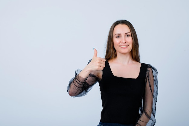 Smiling girl is looking at camera by showing perfect gesture on white background