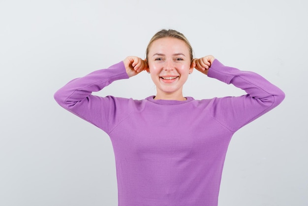 The smiling girl is pulling her ears on white background