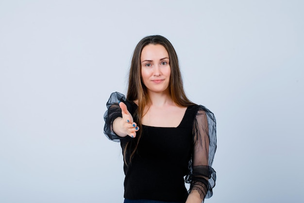 Smiling girl is showing hi gesture by extending hand to camera on white background