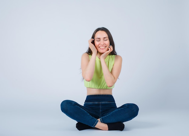 Smiling girl is wishing by sitting on floor on white background