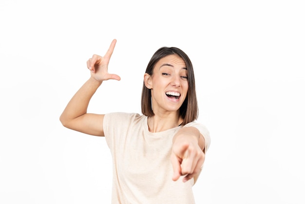 A smiling girl mocking and pointing someone while doing the looser sign whith her hand.