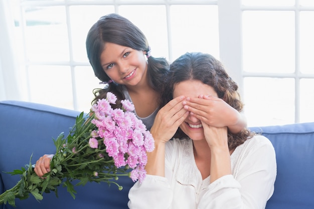 Smiling girl offering flowers to her mother