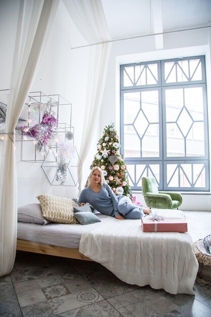 Photo smiling girl sitting on couch near christmas tree at home