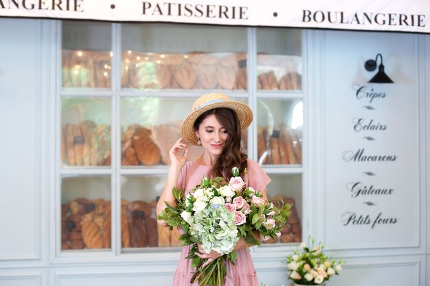 smiling girl stands near window bakery in straw hat with a bouquet of flowers surprise gift