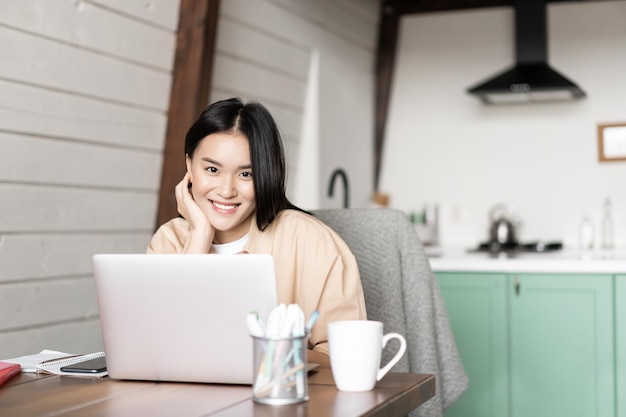 Smiling girl student asian woman working with laptop at home studying at home