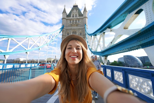 Smiling girl takes selfie photo on Tower Bridge in London United Kingdom