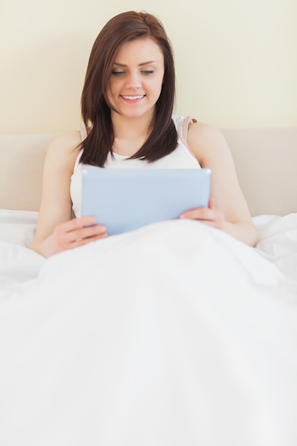 Smiling girl using a tablet pc lying on bed