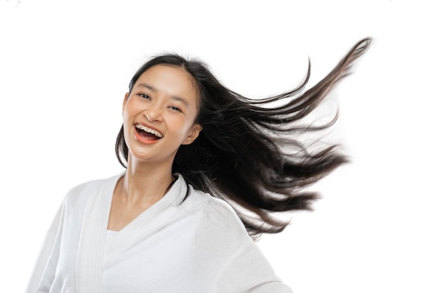 Smiling girl wearing a towel is standing with her long hair blowing by wind