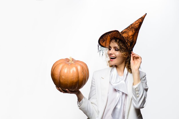 Smiling girl in witch hat with pumpkin preparation halloween holidays woman witch with pumpkin