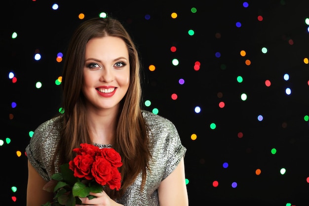 Smiling girl with bouquet of red roses on lights background