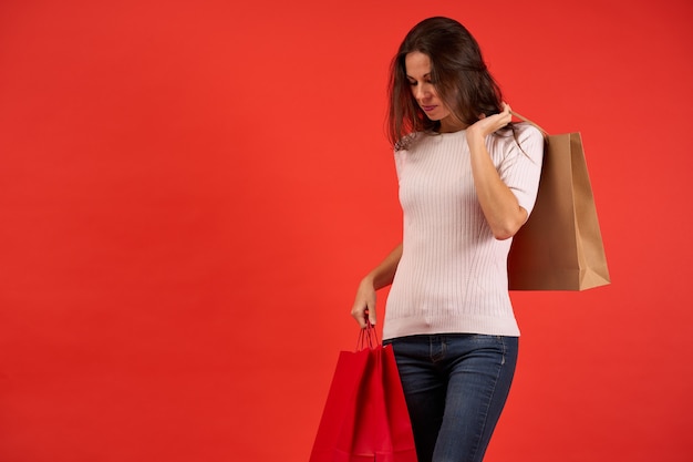 Smiling girl with christmas shopping and christmas bags on orange background