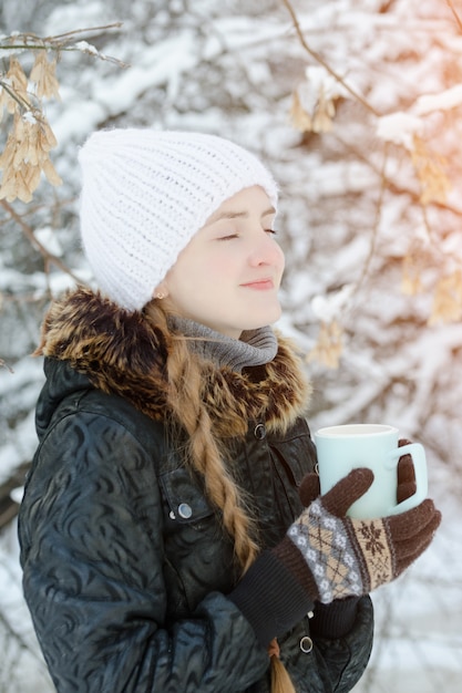 Smiling girl with cup of tea enjoying sun. 