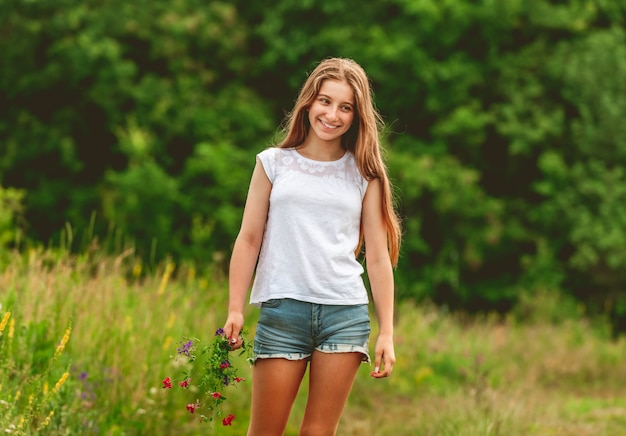 Smiling girl with field flowers bouquet