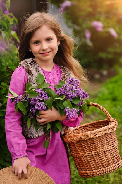 Smiling girl with long blonde hair in lilac Garden Girl with lilac flowers in springtime Gardening