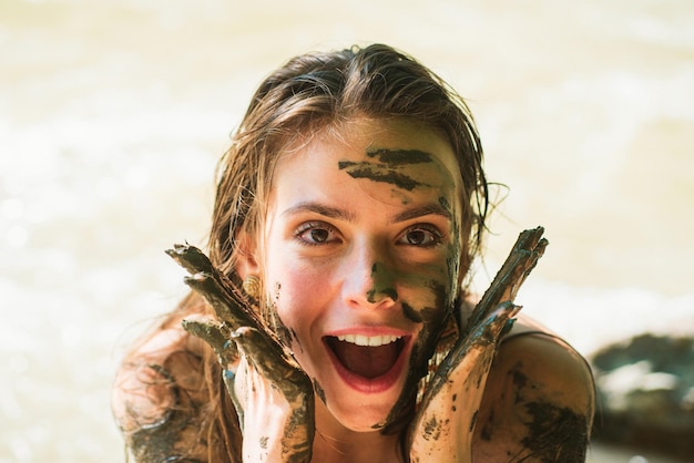 Smiling girl with mud mask muddy hands woman with natural mud mask