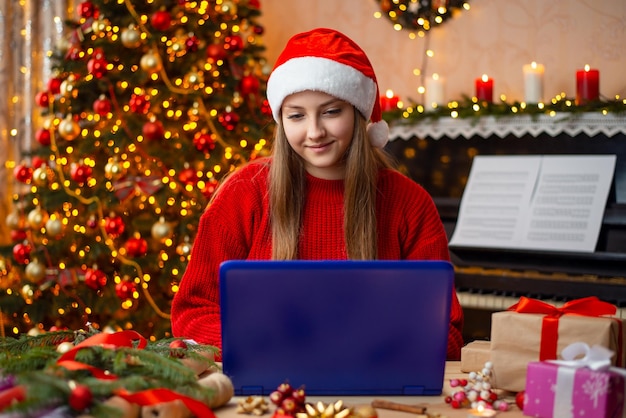 Smiling girl working on the computer in decorated for Christmas living room Christmas celebration concept