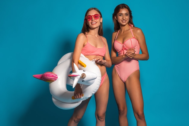 Smiling girls in bathing suits on blue wall