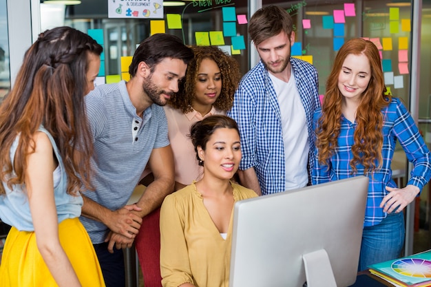 Smiling graphic designers interacting with each other while working at desk