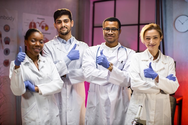 Smiling group of scientists in modern laboratory with male african american leader mix race