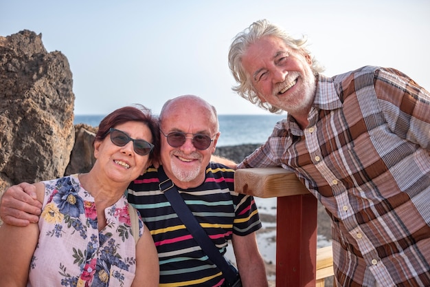 Smiling group of senior people looking at camera enjoying sea excursion. Active lifestyle for three retired people