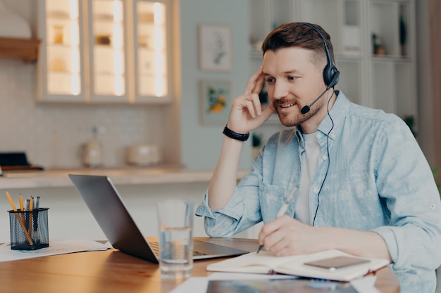 Smiling guy listening attentively online lesson while sitting at home