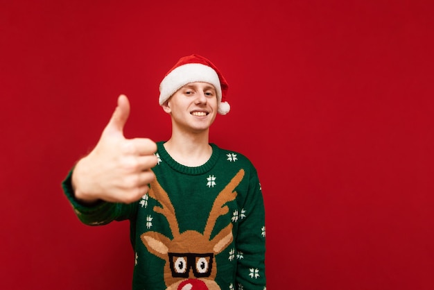 Smiling guy shows gesture like on red background in christmas