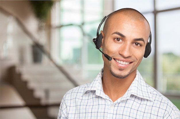 Smiling handsome businessman wearing headset looking at camera isolated on white